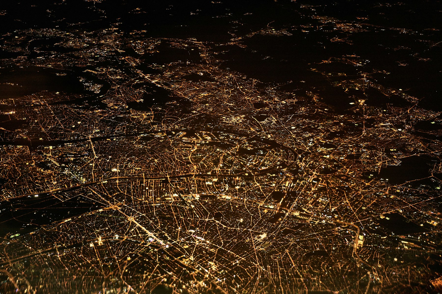 A city street grid glowing gold, seen from high above at night